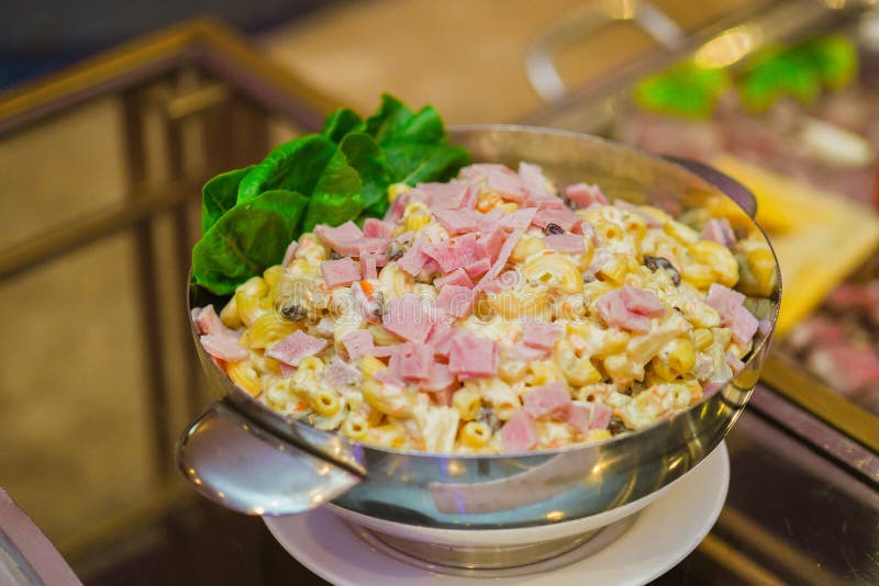Closeup of a Huge Bowl of Pasta Salad with Ham and Mayo on the Table in a Restaurant Stock Photo