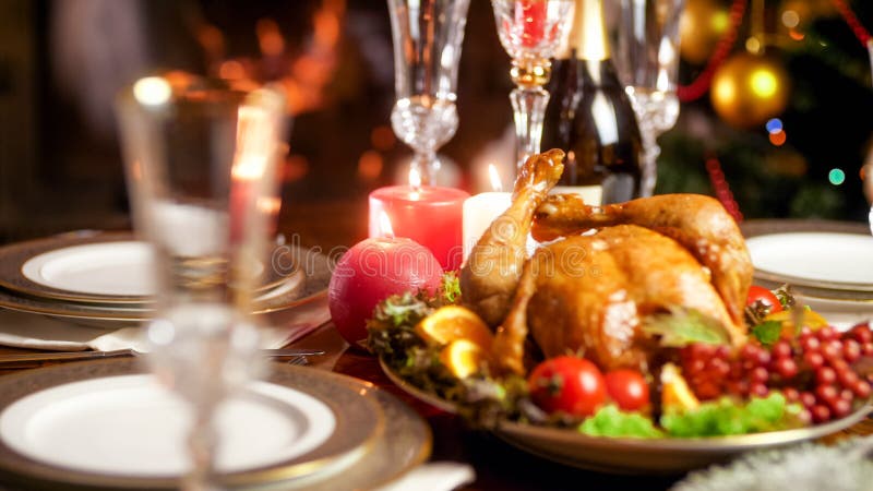 Closeup image of candles burning on served hristmas dinner table with baked chicken