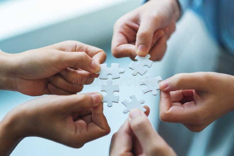 A Group Of People Holding And Putting A Piece Of White Jigsaw Puzzle