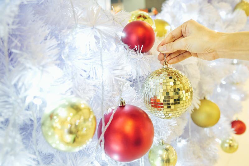 Closeup image of a hand decorating white snow Christmas tree with gold sparkling glitter baubles, disco crystal ball style. stock image Closeup image of a hand decorating white snow Christmas tree with gold sparkling glitter baubles, disco crystal ball style. stock image