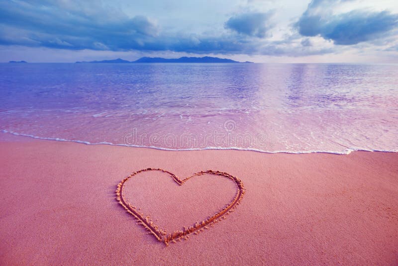 Closeup image of heart symbol written on sand at pink sea sunrise background. Closeup image of heart symbol written on sand at pink sea sunrise background.