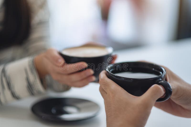 A man and a woman holding two coffee cups together