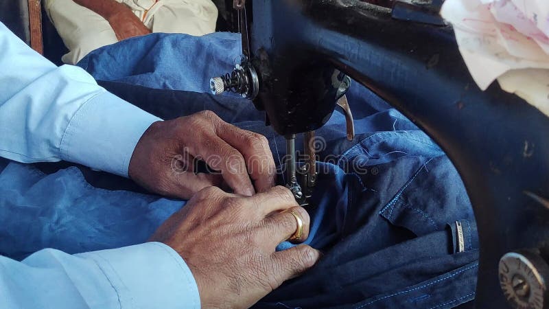 A closeup of an Indian tailor sewing clothes on an old sewing machine stock video footage