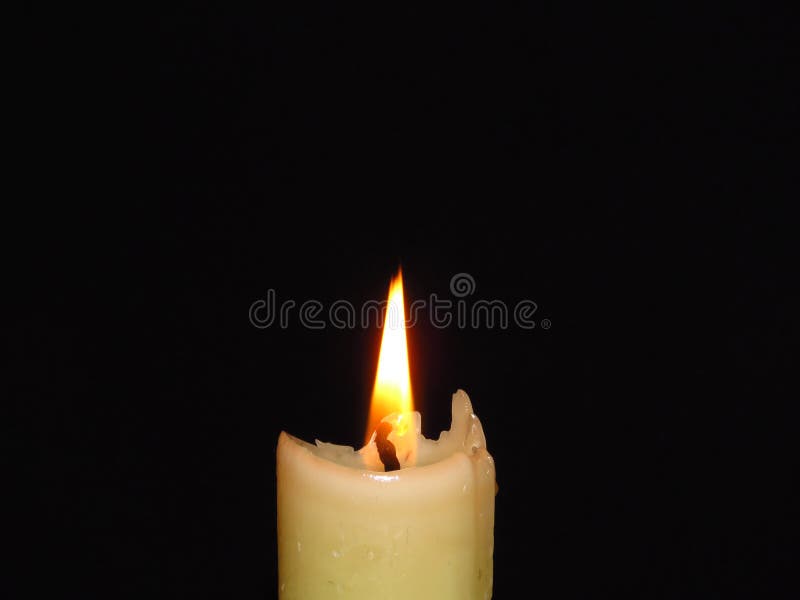 Closeup of an Isolated Burning Candle on Dark Black Background. Flame, Light, Candle Wax