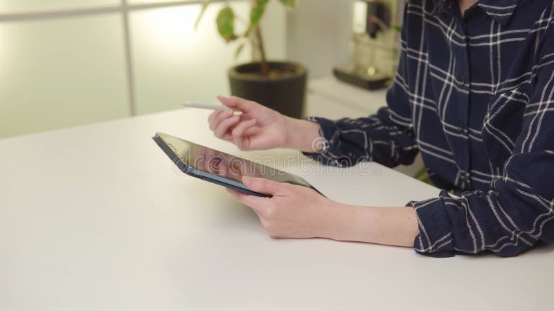 Closeup jeune femme naviguant tablette numérique avec stylet dans un bureau moderne. clips vidéos