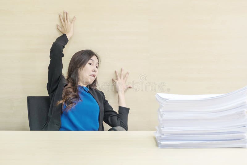 Closeup joke action of working woman are afraid pile of work paper in front of her in work concept on blurred wooden desk and stock images Closeup joke action of working woman are afraid pile of work paper in front of her in work concept on blurred wooden desk and stock images