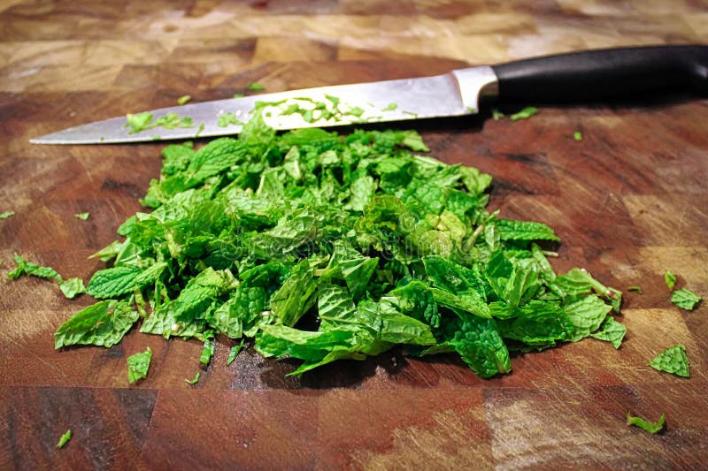 Closeup of a Knife on a Cutting Board with Fresh Green Mint Stock Photo