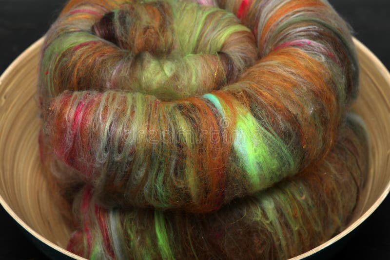 Closeup of lots of beautiful sheep wool fibres rolled up in a roving ready for spinning yarn on a spinning wheel as a hobby