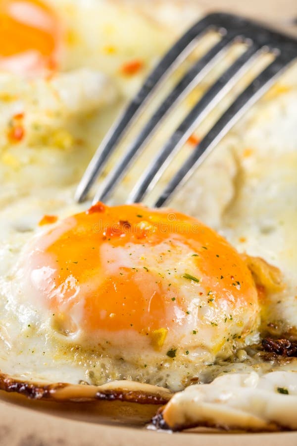 Closeup Macro Fried Egg Yolk with Metal Fork on the Plate Stock Photo