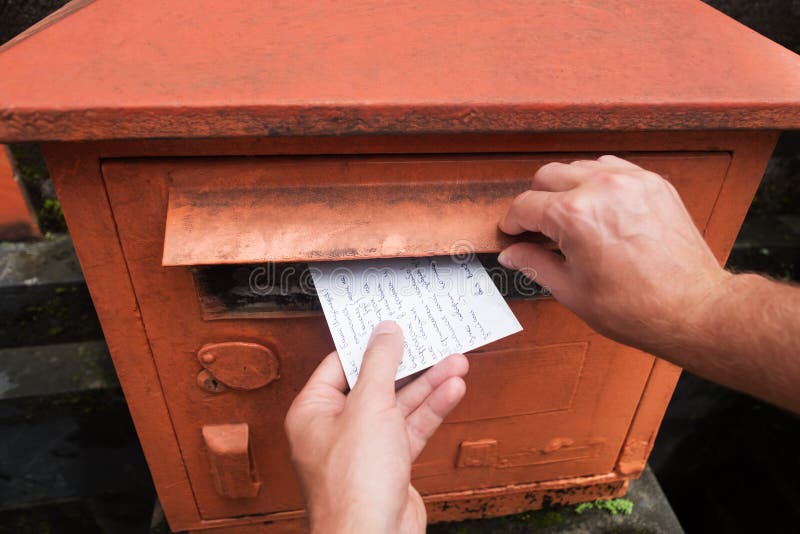 Closeup on a male hand putting a letter in a red letterbox. Concept of vintage type of communication. stock photo Closeup on a male hand putting a letter in a red letterbox. Concept of vintage type of communication. stock photo