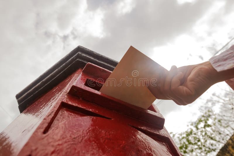 Closeup on a male hand putting a letter in a red letterbox. Concept of vintage type of communication. royalty free stock photo Closeup on a male hand putting a letter in a red letterbox. Concept of vintage type of communication. royalty free stock photo