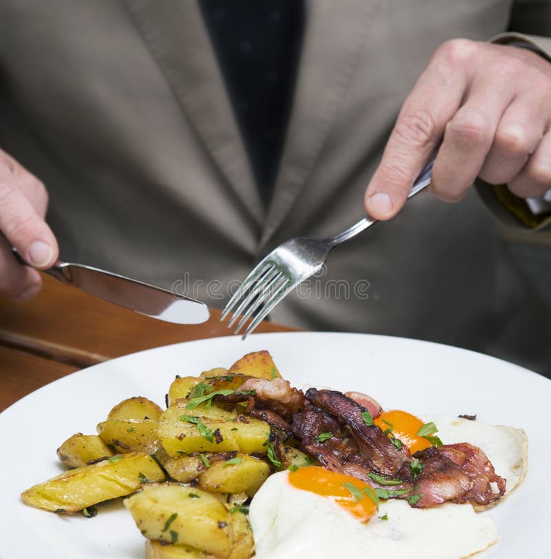 Closeup of Man Eating Fried Eggs, Potatoes and Bacon Stock Image