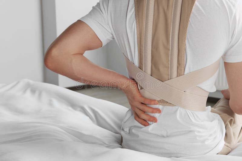 Closeup of Man with Orthopedic Corset Sitting Indoors, Back View Stock