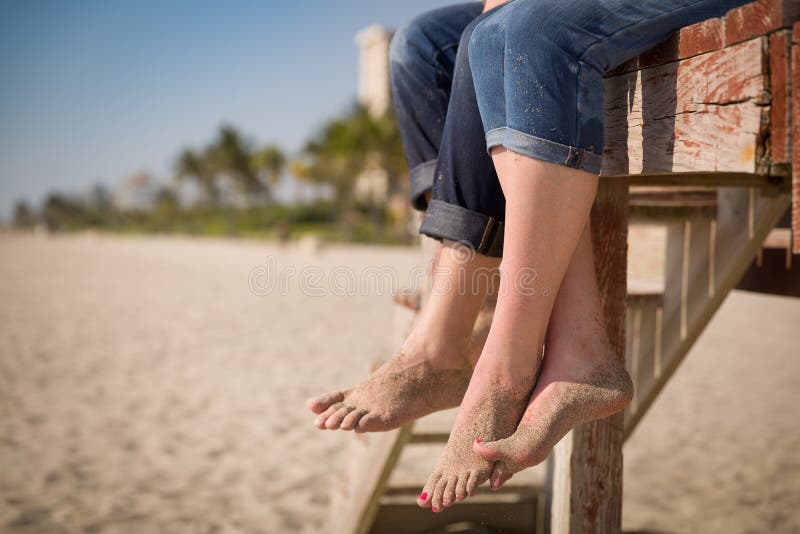 Closeup of Man`s and Woman`s Feet. People Sitting on the Wooden Deck on ...