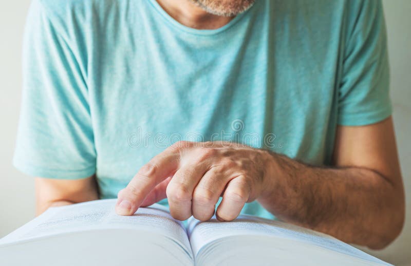 Closeup of man searching for the term in the dictionary, finger pointing to a book page stock photography