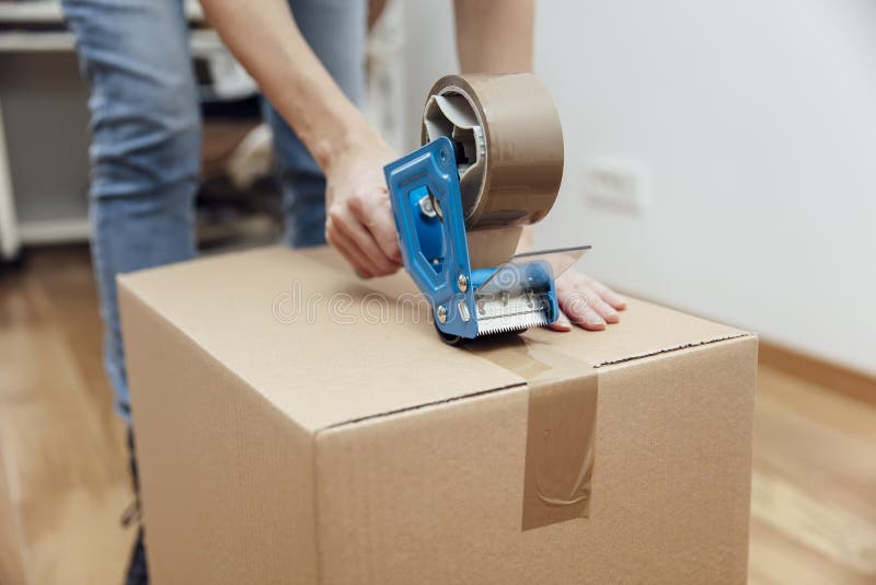 Hands of a man using a tape dispenser to seal a shipping box royalty free stock image Hands of a man using a tape dispenser to seal a shipping box royalty free stock image