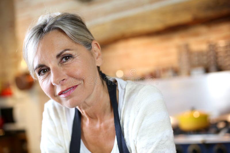 Closeup of mature woman with grey hair standing in kitchen