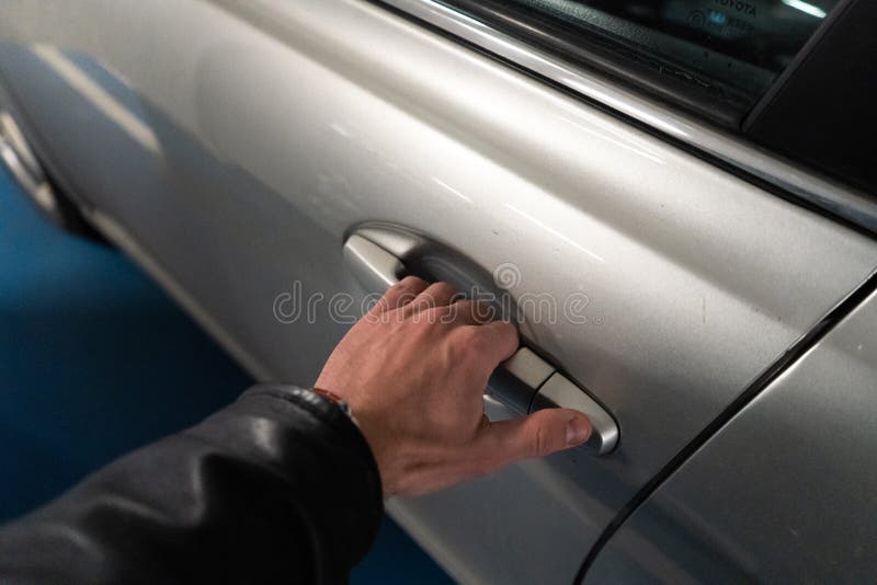 Closeup a men`s hand on the latch of a car door opening it up - Light color car royalty free stock photography Closeup a men`s hand on the latch of a car door opening it up - Light color car royalty free stock photography