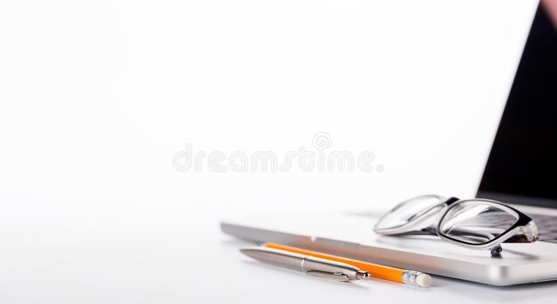 Closeup of an office table featuring a sleek laptop and reading glasses on a clean white surface stock photos