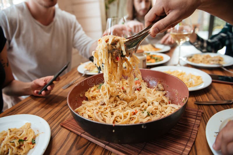 Closeup of People Eating Pasta on the Kitchen at Home Stock Image