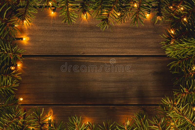 Christmas frame with lights and fir branches on wooden background top view and copy space image