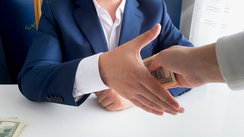 Closeup image of corrupted politician shaking hand with person and receiving bribe. Closeup photo of corrupted politician shaking hand with person and receiving stock photo Closeup image of corrupted politician shaking hand with person and receiving bribe. Closeup photo of corrupted politician shaking hand with person and receiving stock photo