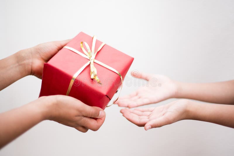Closeup photography of hands holding a red box gift and little hands receiving on white background