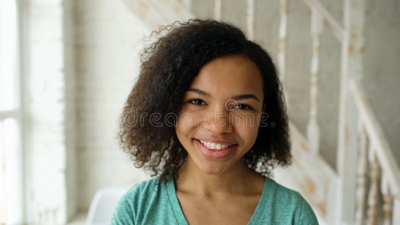 Closeup portrait of beautiful african american girl laughing and looking into camera at home