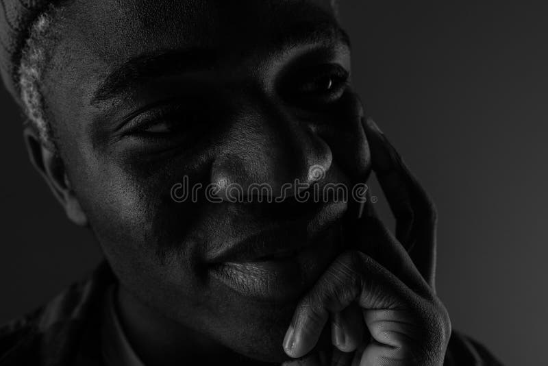 Closeup portrait of a black smiling American man with big lips in black and white light.