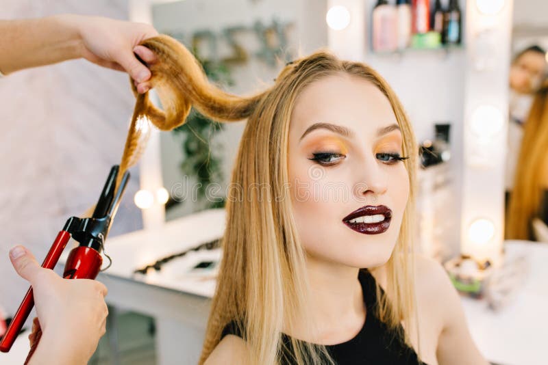 Closeup portrait charming blonde woman preparing to celebration, party in beauty salon. Stylish makeup, making hairstyle