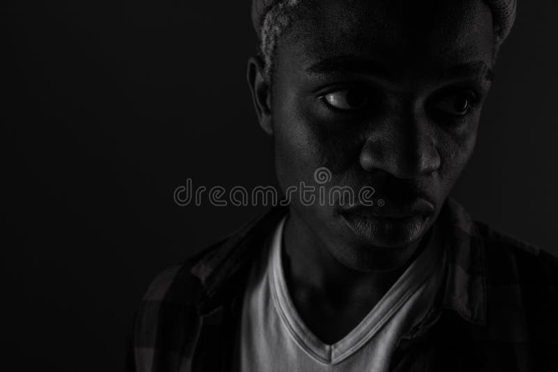 Closeup portrait of a charming handsome black man with closed eyes in black and white light.