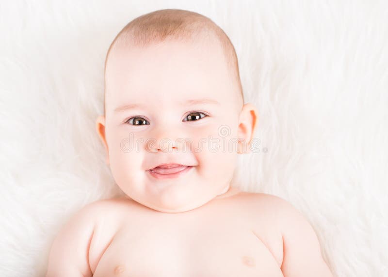Closeup portrait of a cute smiling baby lying on white fur