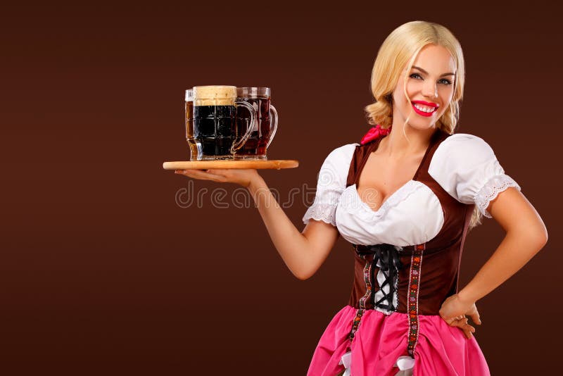 Closeup portrait of Oktoberfest girl - waitress, wearing a traditional Bavarian dress, serving big beer mugs on brown stock photo Closeup portrait of Oktoberfest girl - waitress, wearing a traditional Bavarian dress, serving big beer mugs on brown stock photo