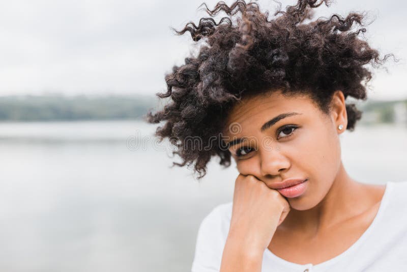 Closeup portrait of pensive beautiful African American young woman posing outdoors, have sad face. Beautiful young dark-skinned