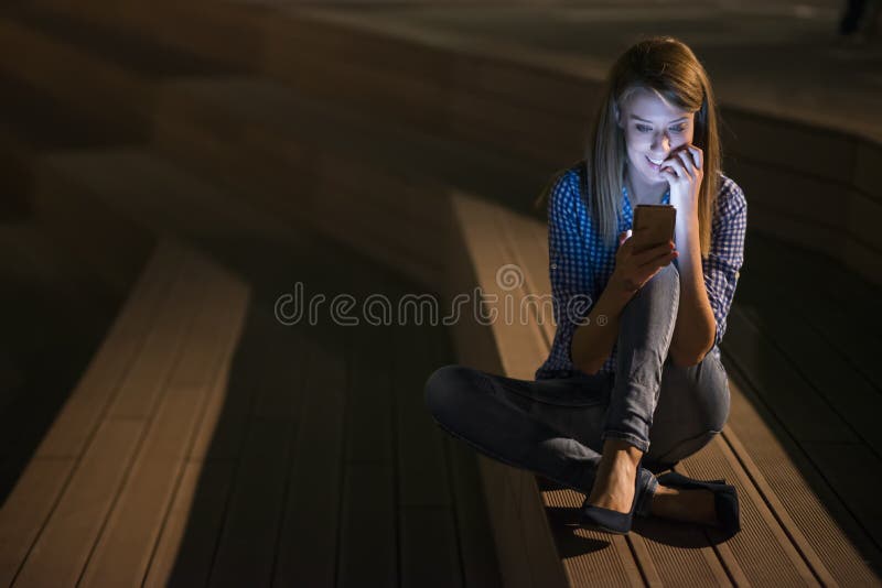 Closeup portrait smiling or laughing young freelancer woman looking at phone seeing good news or photos with nice emotion stock photography Closeup portrait smiling or laughing young freelancer woman looking at phone seeing good news or photos with nice emotion stock photography