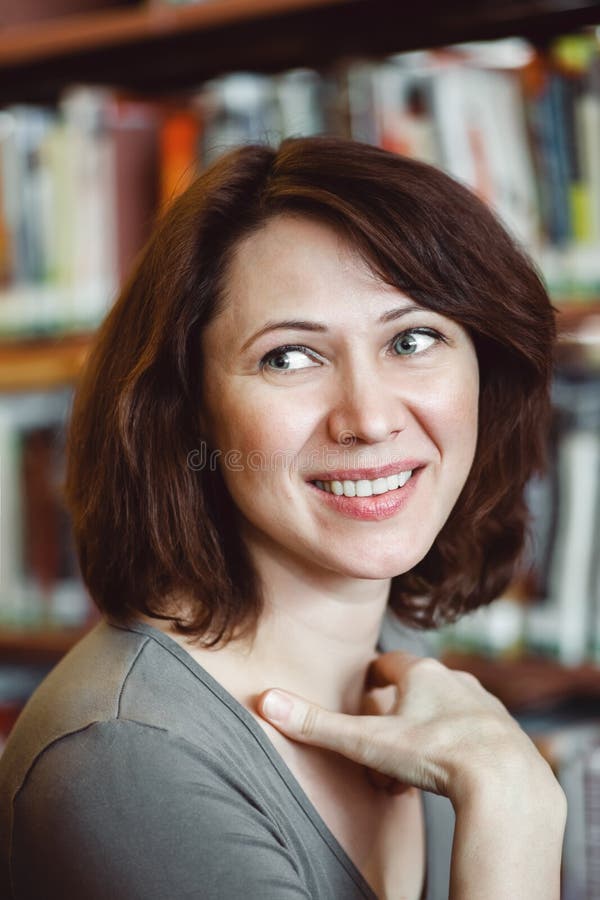 Closeup portrait of smiling middle age mature woman student in library looking away, teacher librarian profession