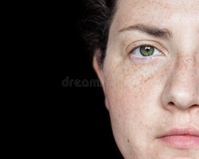Closeup Portrait of Woman with Freckles and Green Eyes Isolated on a Black Background: Half of Face Visible on Right Side of Frame