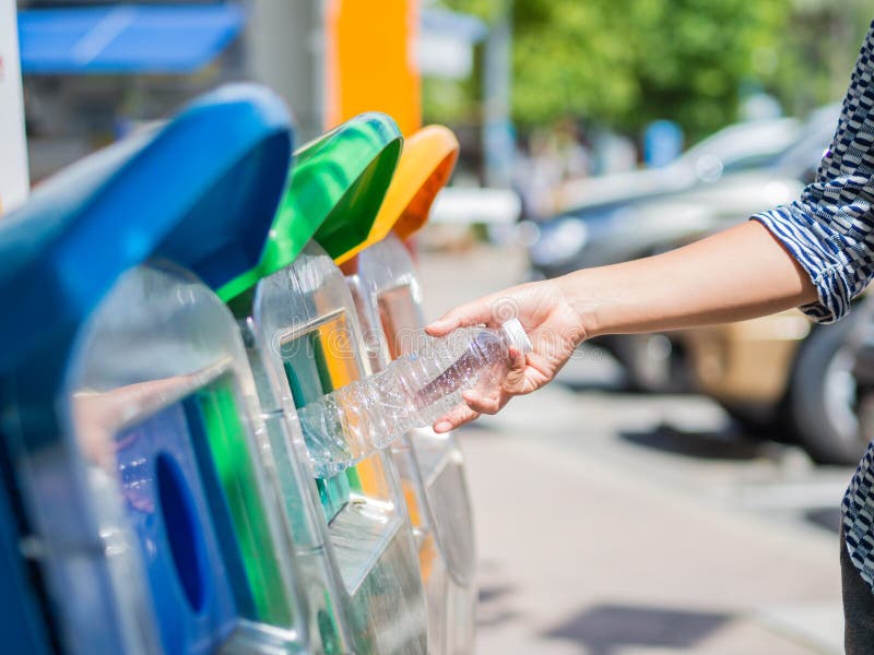 Closeup portrait woman hand throwing empty plastic water bottle in recycling bin...