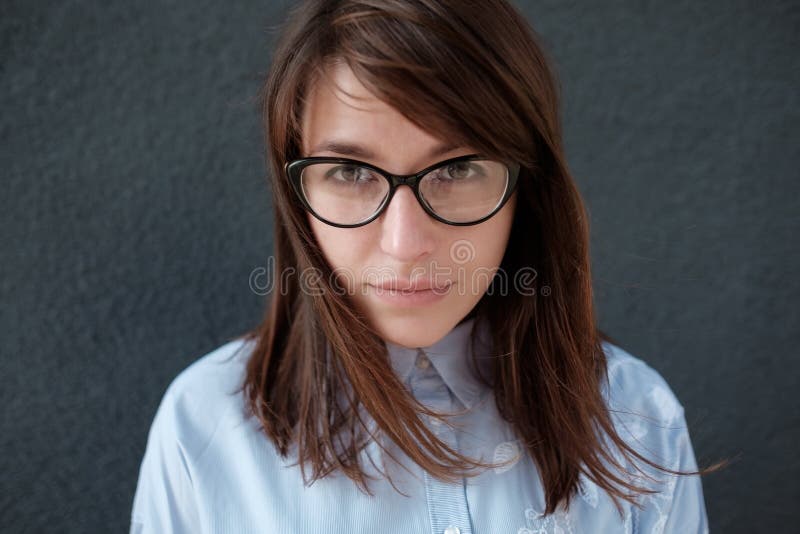 Closeup portrait of young attractive woman with glasses on a dark background.