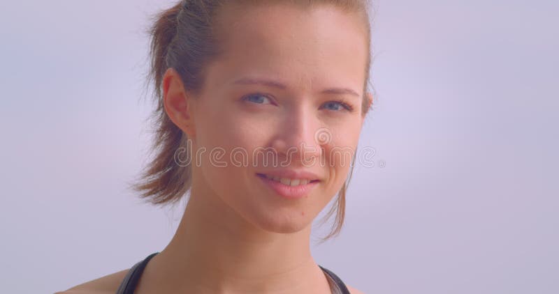 Closeup portrait of young cute female jogger in sportswear looking forward being determined with blue sky on the