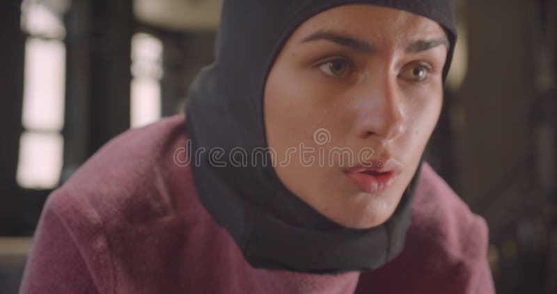 Closeup portrait of young motivated athletic muslim female in hijab working out in gym indoors