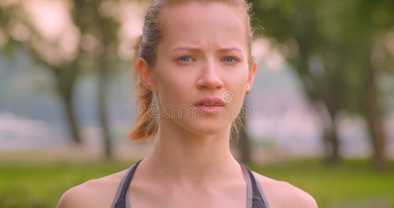 Closeup portrait of young pretty sporty fitness girl in the park in urban city outdoors