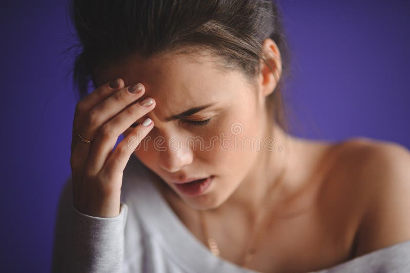 Closeup portrait young upset sad woman thinking deeply about something with headache holding her hands stock photo Closeup portrait young upset sad woman thinking deeply about something with headache holding her hands stock photo