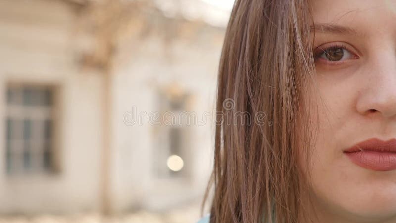 Closeup portrait of a young woman standing in the wind. The spring wind plays with the girl`s hair. Slow motion