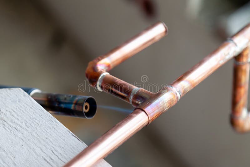 Closeup professional soldering copper pipes gas burner. Concept installation, plumbing replacement, solder flux paste, pipeline