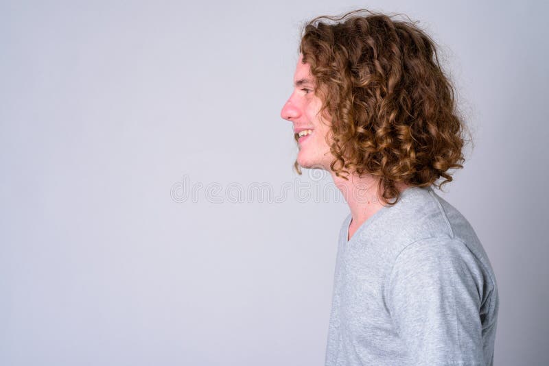 Studio shot of young handsome man with long curly hair against white background. Studio shot of young handsome man with long curly hair against white background