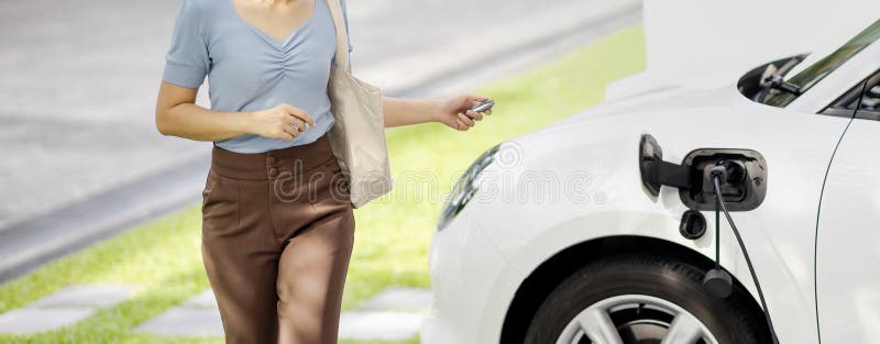 Closeup progressive woman recharge her EV car at home charging station.