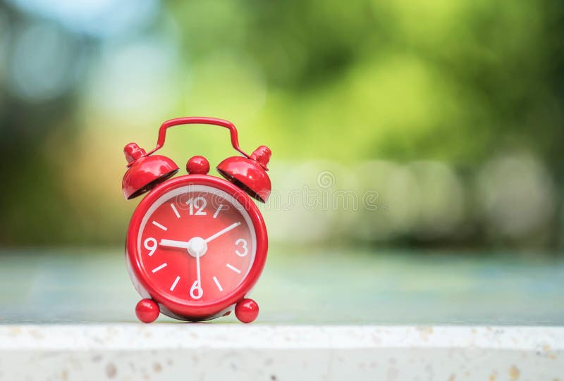 Closeup red alarm clock display seven hours and fifteen minutes on screen on blurred marble desk and park view background royalty free stock photo Closeup red alarm clock display seven hours and fifteen minutes on screen on blurred marble desk and park view background royalty free stock photo