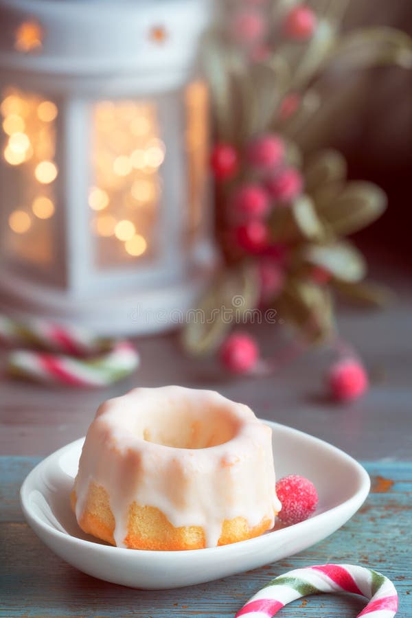 Closeup on red cup of milk with Christmas deer design, bundt cake, Xmas lights in lantern and berries