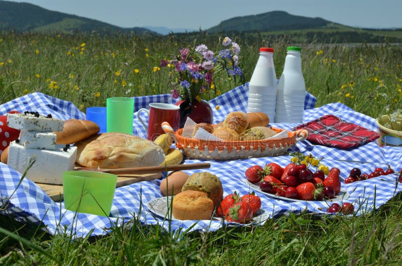 Closeup of rich picnic breakfast or brunch on mountain meadow with hills in background. Closeup of rich picnic breakfast or brunch on mountain meadow with hills in background